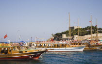 Cruise boats moored in harbour with fortified building on tree covered rise beyond.TurkishAegeancoastresortSummersunshineearly Summer seasonholidaydestinationdestinations ElladaEuropeanSou...