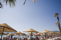 Marmaris on the Turkish Riviera in early Summer season.  Parasols and sunbeds for rent on busy beach in morning sun.Turkish RivieraresortholidayholidaymakersDestinationCrowdedcrowdsun umbrella...