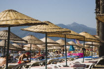 Marmaris on the Turkish Riviera in early summer season.   Parasols and sunbeds for rent on busy beach in morning sun.   resortholidayholidaymakersDestinationCrowdedcrowdsun umbrellashadesun l...