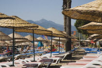 Marmaris on the Turkish Riviera in early summer season.  Parasols and sunbeds for rent on busy beach in morning sun.resortholidayholidaymakersDestinationCrowdedcrowdsun umbrellashadesun loung...