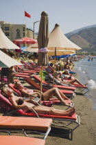 Marmaris on the Turkish Riviera in early Summer season. Female tourists sunbathing on line of hire sunbeds on beach.coastcoastalresortholidayholidaymakerssunrelaxingleisuresuntansun lounger...