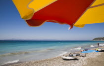 Ixia beach resort outside Rhodes town  a popular destination for water sports with part seen red and yellow striped sun umbrella against backdrop of cloudless blue sky and distant Turkish coast on bri...