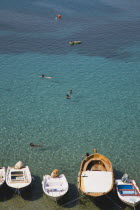 Lindos.  View over clear shallow water of bay with line of moored boats in the foreground and tourists swiming in late afternoon sunshine.Greek IslandsAegeanRodicoast coastalseaswimbathingreso...