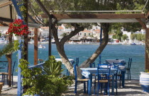 Pythagorio.  Greek restaurant with tables and chairs beneath canopy overlooking bay in early summer season.AegeanGreek IslandsPythagorionharbour Summerseacoast coastalresortholidaypackagetr...