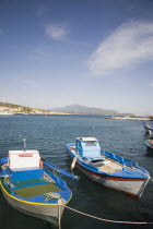 Pythagorio.  Small  blue and white painted fishing boats tied up at harbour with coast of Turkey only five kilometres away in background.  Windswept clouds in blue sky above.AegeanGreek IslandsPyth...