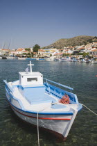 Pythagorio.  Small blue and white fishing boat with cross on cabin top and red trim moored in Pythagorio bay with view towards waterfront behind.AegeanGreek IslandsPithagorion Pythagorioncoast coa...