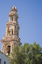 St Michael Panormitis monastery in Southern Symi.  Site of pilgrimage from the 12th Century.  Highly decorated Baroque bell tower against bright summer blue sky.AegeanGreek IslandsSimicoast coasta...