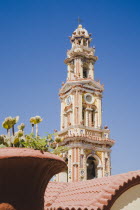 St Michael Panormitis monastery in Southern Symi.  Site of pilgrimage from the 12th Century.  Highly decorated Baroque bell tower and roof detail against bright summer blue sky.AegeanGreek IslandsS...