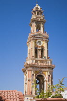 St Michael Panormitis monastery in Southern Symi.  Site of pilgrimage from the 12th Century.  Highly decorated Baroque bell tower against bright summer blue sky.AegeanGreek IslandsSimicoast coasta...