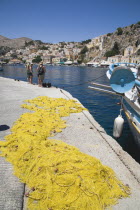 Yialos harbour  the main port of Symi island with yellow fishing nets spread out across stone jetty.AegeanGreek IslandsSimicoast coastalseaSummerpackageholidayresortvacationtripdestination...