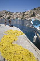 Yialos harbour  the main port of Symi island with yellow fishing nets spread out across stone jetty.AegeanGreek IslandsSimicoast coastalseaSummerpackageholidayresortvacationtripdestination...