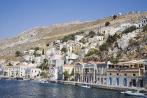 Yialos.  Buildings on waterfront and steep  rocky hillside behind. AegeanGreek IslandsSimicoast coastalseaSummerpackageholidayresortvacationtripdestinationDestinations ElladaEuropeanSou...