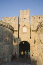 Yialos.  Tourists at arched entrance of fortified gateway with crenellated walls.AegeanGreek IslandsSimicoast coastalseaSummerpackageholidayresortvacationtripdestinationDestinations Ellad...