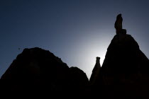 Turkey, Cappadocia, Goreme, Hot air balloons in flight over landscape, Silhouette of rock shapes with hot air balloon in the distance.