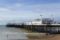 England, East Sussex, Brighton, The Pier at low tide with a woman walking towards the water.