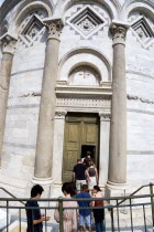 ITALY, Tuscany, Pisa, The Campo dei Miracoli or Field of Miracles with a tour party of tourists at the entrance to the Leaning Tower or Torre Pendente belltower.