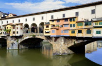 ITALY Tuscany Florence Ponte Vecchio medieval bridge across River Arno with view of merchant's shops that line bridge and hang over the water below.