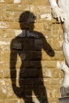 ITALY, Tuscany, Florence, Shadow of the replica Renaissance statue of David by Michelangelo on the wall of the Palazzo Vecchio in the Piazza della Signoria.