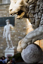 ITALY, Tuscany, Florence, Replica of Renaissance statue of David by Michelangelo in the Piazza della Signoria beside the Palazzo Vecchio beyond statue of lion with paw on cannonball.