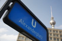 Germany, Berlin, Alexanderplatz, U Bahn sign for Alexanderplatz with Fernsehturm & office building in background. 