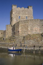 Ireland, County Antrim, Carrickfergus, Castle exterior with a boat moored in the foreground.