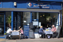 England, East Sussex, Brighton, people sate on tables outsdie the Time Out cafe in East Street.