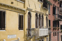 Italy, Veneto, Venice, Restored facades of canalside buildings painted pastel pink, terracotta and yellow with window balconies and shutters in late summer sunshine.