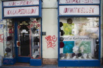 Hungary, Pest County, Budapest, graffiti on hat shop facade around window display.