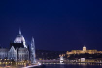 Hungary, Budapest, View along the River Danube at night with the Parliament building on the left, the Chain Bridge and the Royal Palace on the right all illuminated brightly.