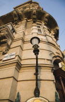 Hungary, Pest County, Budapest, part view of renovated apartment exterior facade with street sign and street lamp. View from ground level looking upwards to balcony and roof detail.