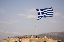 Greece, Attica, Athens, Acropolis, Greek flag flying with tourists admiring view of the city.