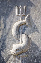 Greece, Athens, Close cropped view of stone carving of sea creature curved around trident.