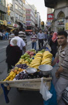 Turkey, Istanbul, Sultanahmet, Fresh fruit stall beside tramway on busy street.