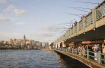 Turkey, Istanbul, Sultanahmet, View towards Galata Tower with men fishing from Galata bridge above fish restaurants below. 