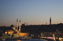 Turkey, Istanbul, Sultanahmet, The Golden Horn. The New Mosque or Yeni Camii at left, the Galata Bridge, and Suleymaniye Mosque at right. Buildings illuminated at dusk.