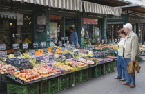 Austria, Vienna, The Naschmarkt, Customers selecting fresh fruit from display on market stall that includes nectarines, peaches, plums, grapes and mangoes.