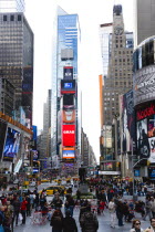 Usa, New York, Manhattan, People walking in Times Square at the junction of 7th Avenue and Broadway below buildings with advertising on large video screens.