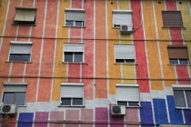 Albania, Tirane, Tirana, Part view of exterior facade of apartment block painted in stripes of different colours, with multiple windows.