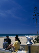 Portugal, Algarve, Praia da Rocha, Veiw along the beach with a telescope and four young men in the foreground.