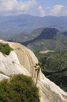 Mexico, Oaxaca, Hierve el Agua, Tourist standing on limestone cliff looking out over surrounding landscape.