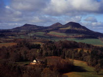 Scotland, Borders, Melrose, Eildon Hills circa 422 metres, from Scotts View.  Rooftops of house in foreground and agricultural land bordered by trees.