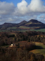 Scotland, Borders, Melrose, Eildon Hills circa 422 metres, from Scotts View.  Rooftops of house in foreground and agricultural land bordered by trees.