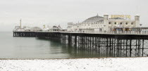 England, East Sussex, Brighton, Pier during winter with snow on the beach.