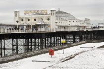 England, East Sussex, Brighton, Pier during winter with snow on the beach.