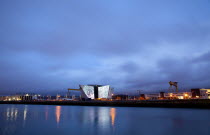 Ireland, North, Belfast, Titanic Quarter, Visitor centre designed by Civic Arts & Eric R Kuhne, illuminated at night.