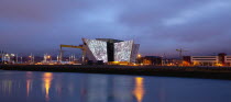 Ireland, North, Belfast, Titanic Quarter, Visitor centre designed by Civic Arts & Eric R Kuhne, illuminated at night.