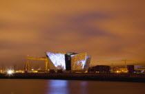 Ireland, North, Belfast, Titanic Quarter, Visitor centre designed by Civic Arts & Eric R Kuhne, illuminated at night.