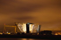 Ireland, North, Belfast, Titanic Quarter, Visitor centre designed by Civic Arts & Eric R Kuhne, illuminated at night.