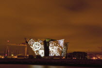 Ireland, North, Belfast, Titanic Quarter, Visitor centre designed by Civic Arts & Eric R Kuhne, illuminated at night.