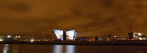 Ireland, North, Belfast, Titanic Quarter, Visitor centre designed by Civic Arts & Eric R Kuhne, illuminated at night.